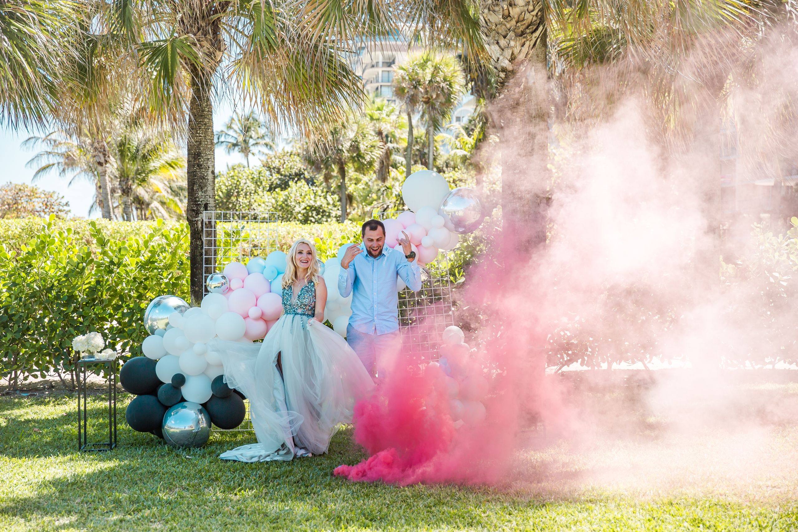 Julia and Slava Di, founders of Cloud Nine, at a gender reveal with pink smoke and balloons