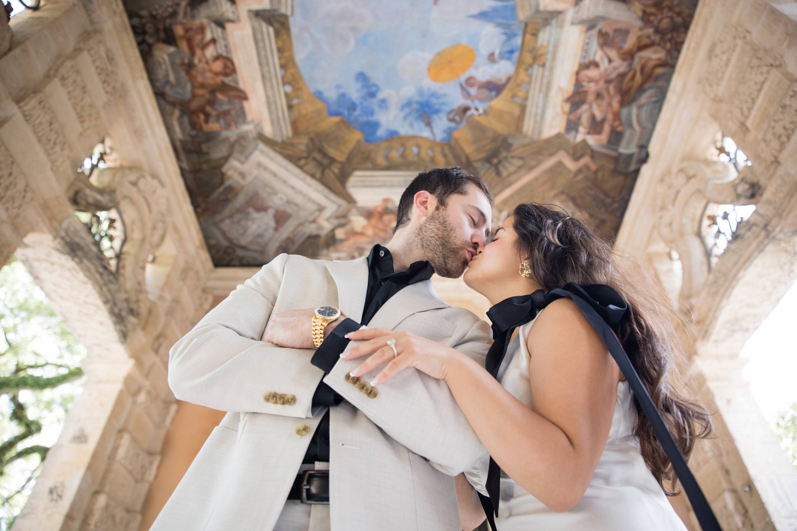 Couple embracing beneath ornate historic architecture