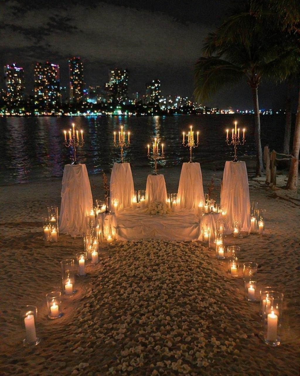 Aisle of candles and white fabric leading to gold candelabras