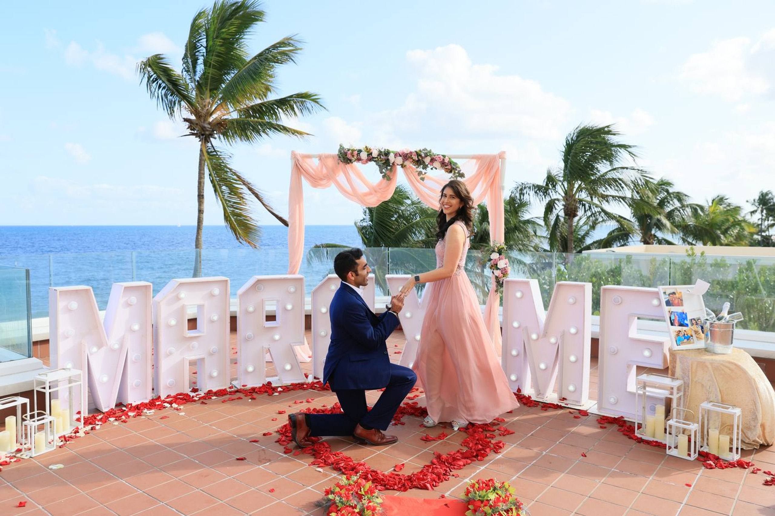 Palm-framed beach proposal with red letters