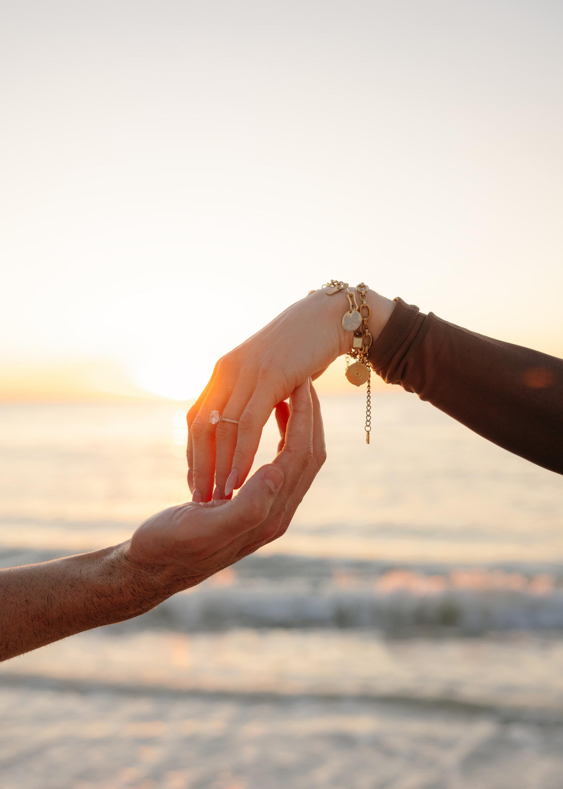 Engagement ring held against warm sunset light