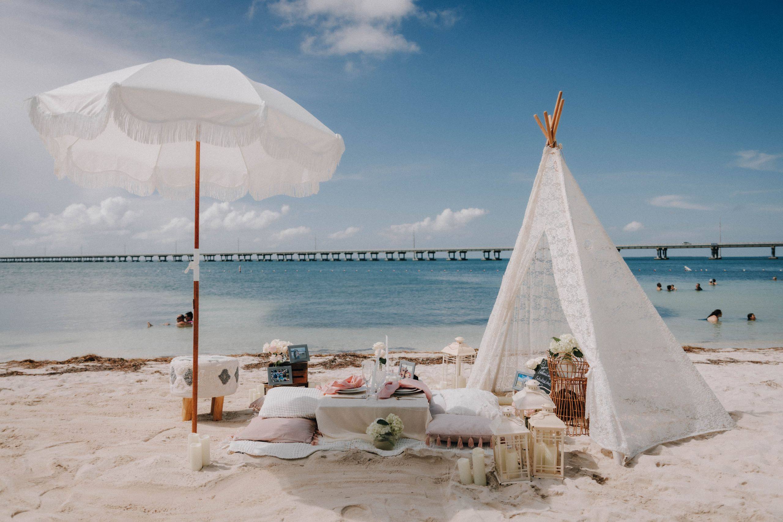 White beach picnic beneath a sail beside turquoise water